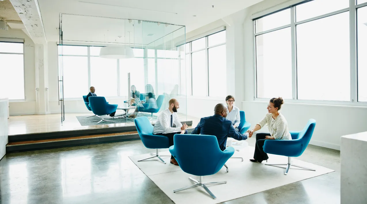 A group sits around a small table in a modern office. 