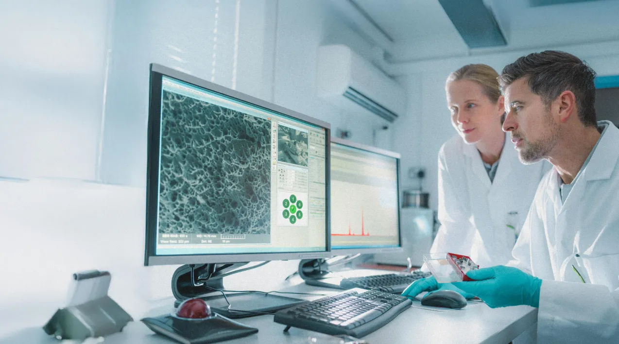 Two scientists looking at data on a monitor