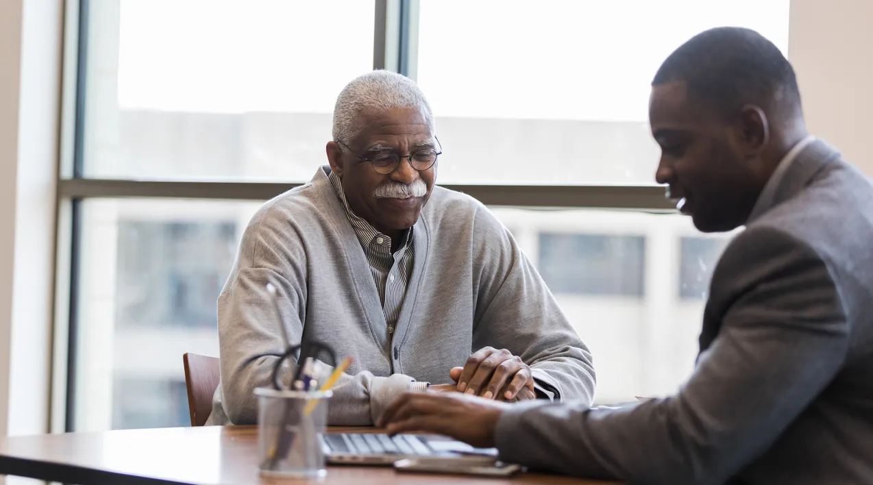 A financial advisor sits with a client at a desk. 