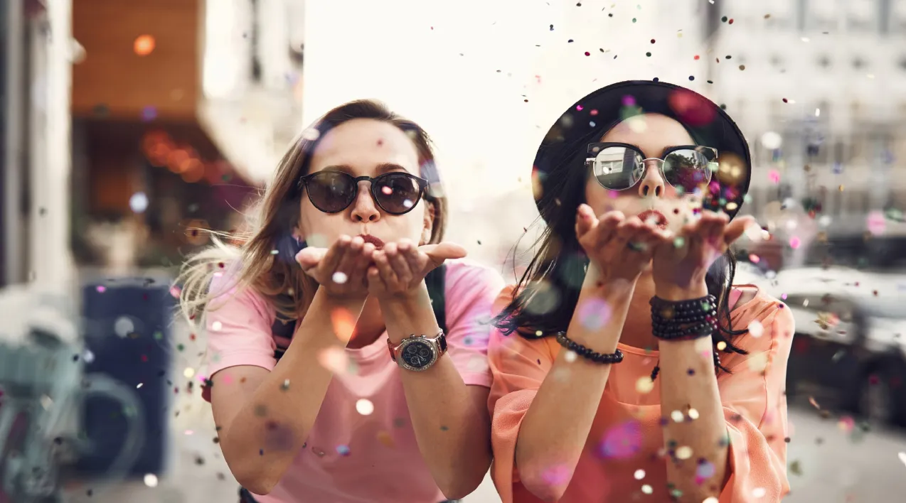 People blowing confetti at camera