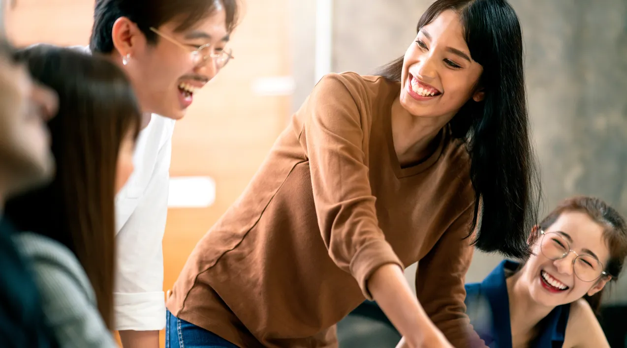 A smiling team collaborates around a table.