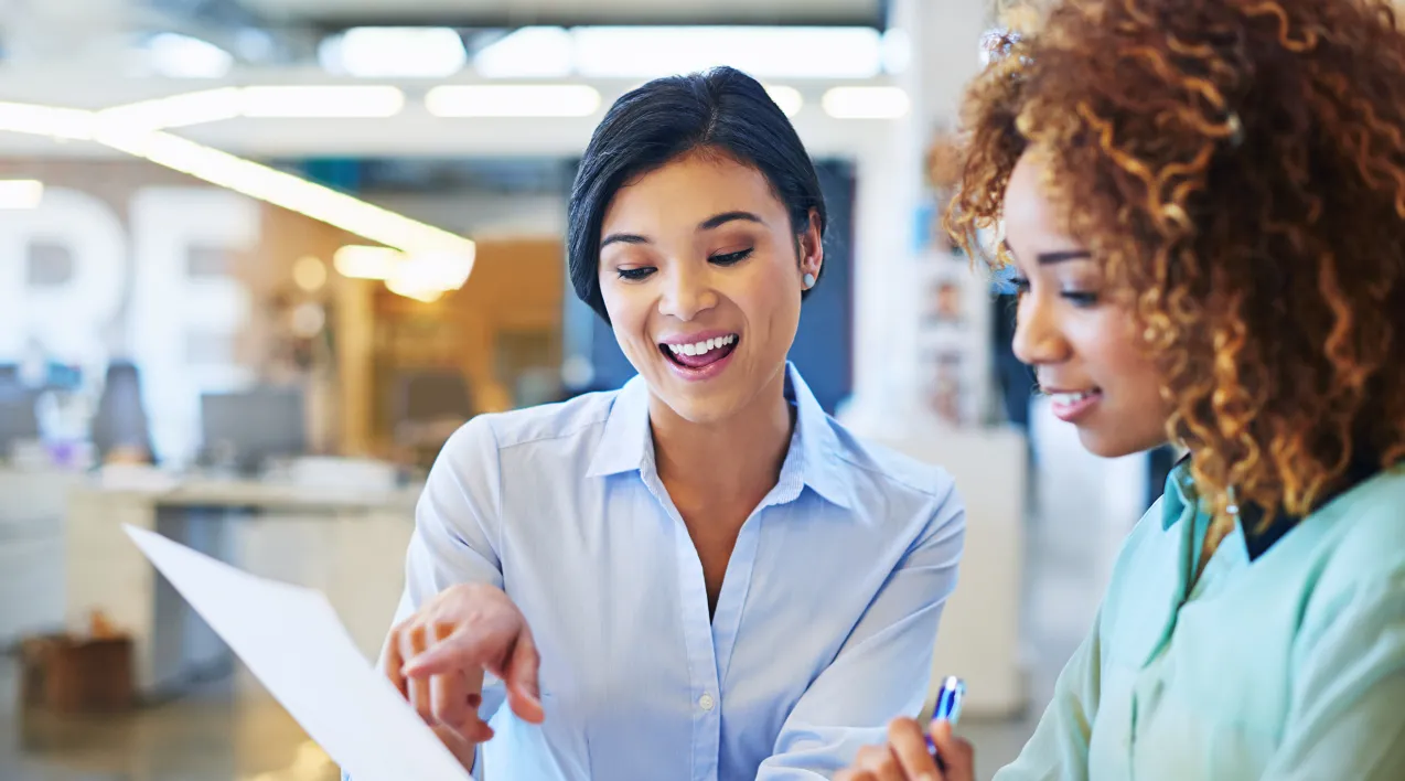 Two women review a document together.