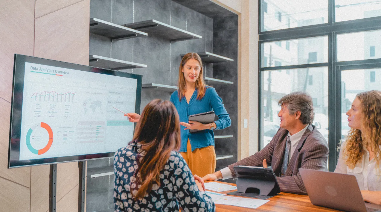 Woman pointing to a monitor in a meeting room