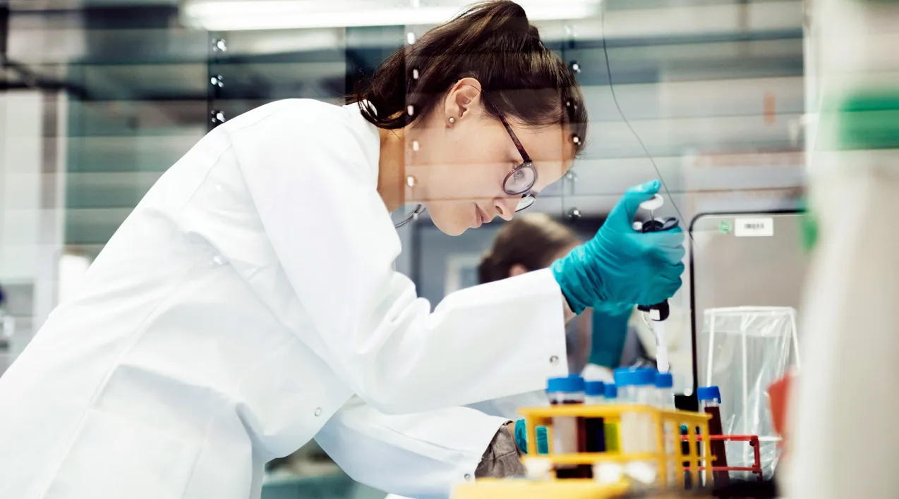 A scientist pipes liquid into vials.