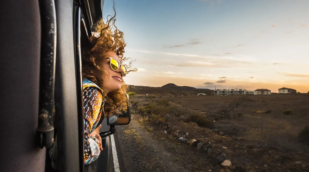 A woman leans out of the window of a vehicle on a freeway.